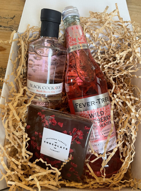 Bush Berry Gift Hamper with Bush Berry Gin, Fever-Tree Wild Raspberry tonic water, and Southern Forests Chocolate Co dark raspberry chocolate -- surrounded by shredded paper packaging and box.